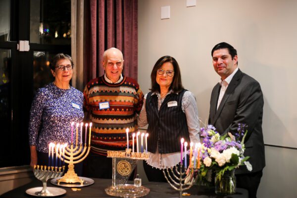Member of The Selfhelp Home Board of Directors and Executive Team post with Menorahs on Chanukah