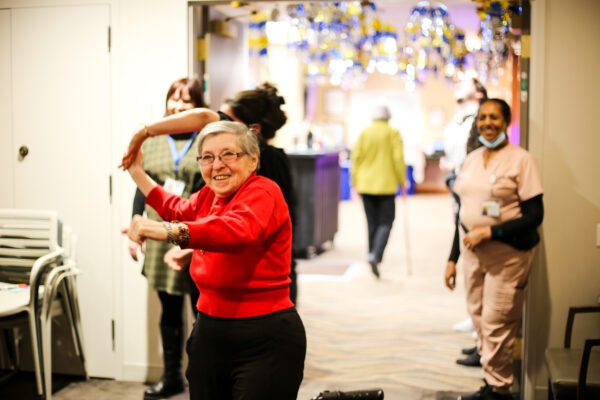 Selfhelp resident in red sweater dancing at a holiday party